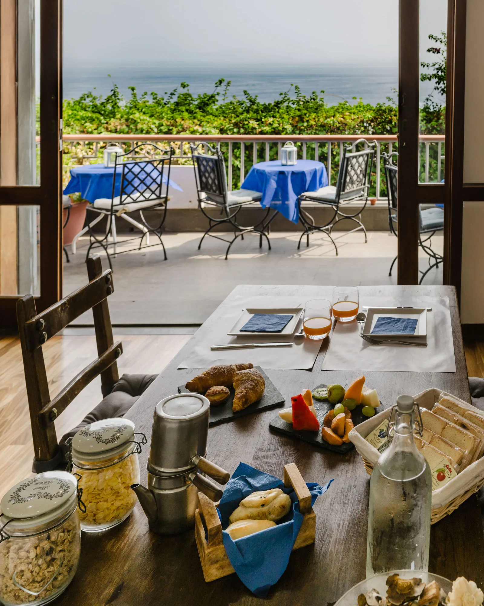 Colazione apparecchiata sulla terrazza, con caffettiera napoletana e vista sul mare