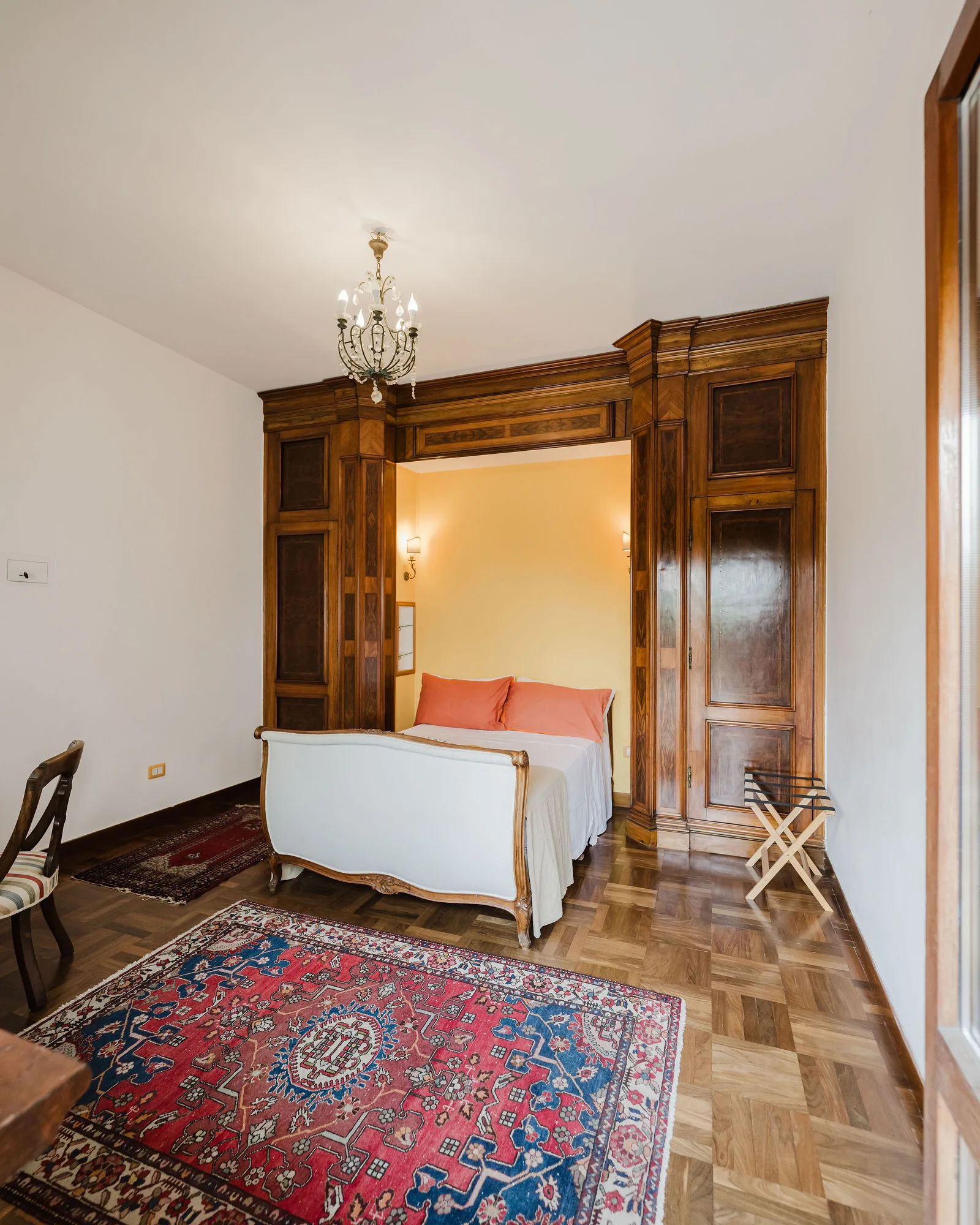 La camera Orange con la boiserie in noce e il lampadario