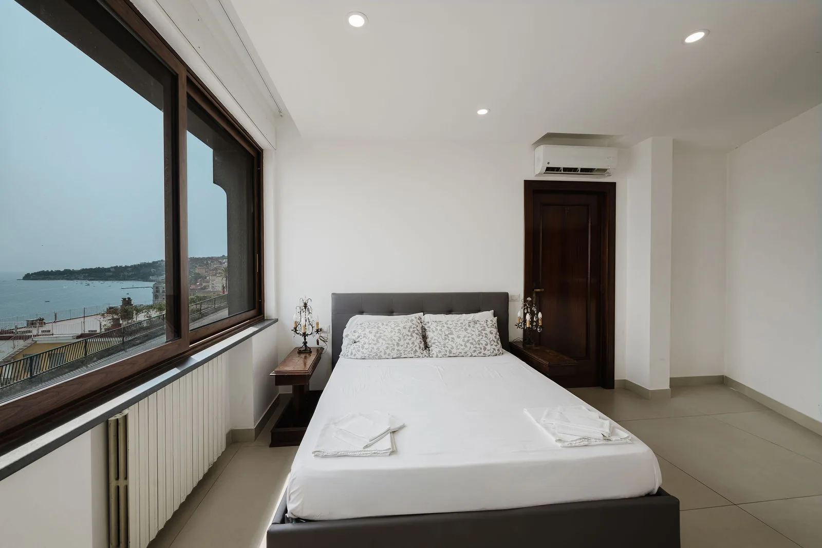 Camera moderna con letto matrimoniale e grande finestra sulla baia di Napoli